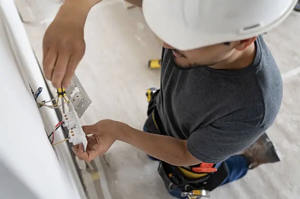 An electrician testing a panel with a multimeter on a sunny jobsite